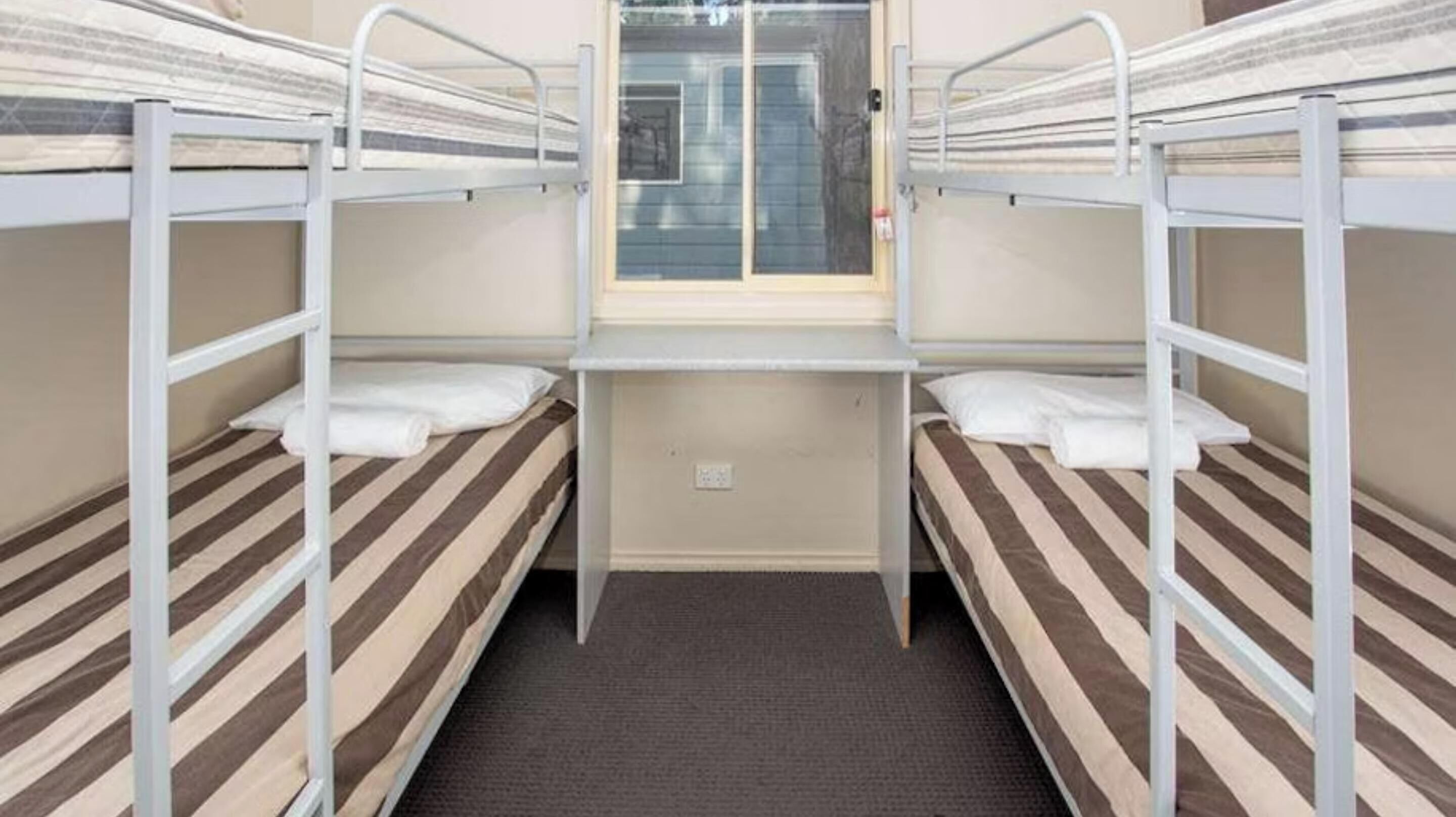 Un dormitorio con literas, una ventana y piso alfombrado.