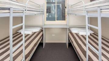 Un dormitorio con literas, una ventana y piso alfombrado.