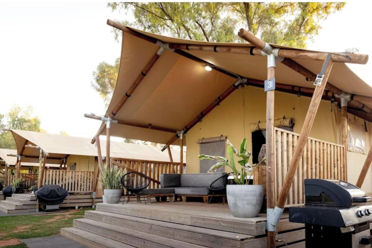 Un espacio al aire libre cubierto con una parrilla, un sofá y plantas en macetas.