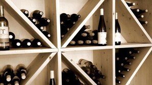 Prateleiras de adega com diversas garrafas de vinho.