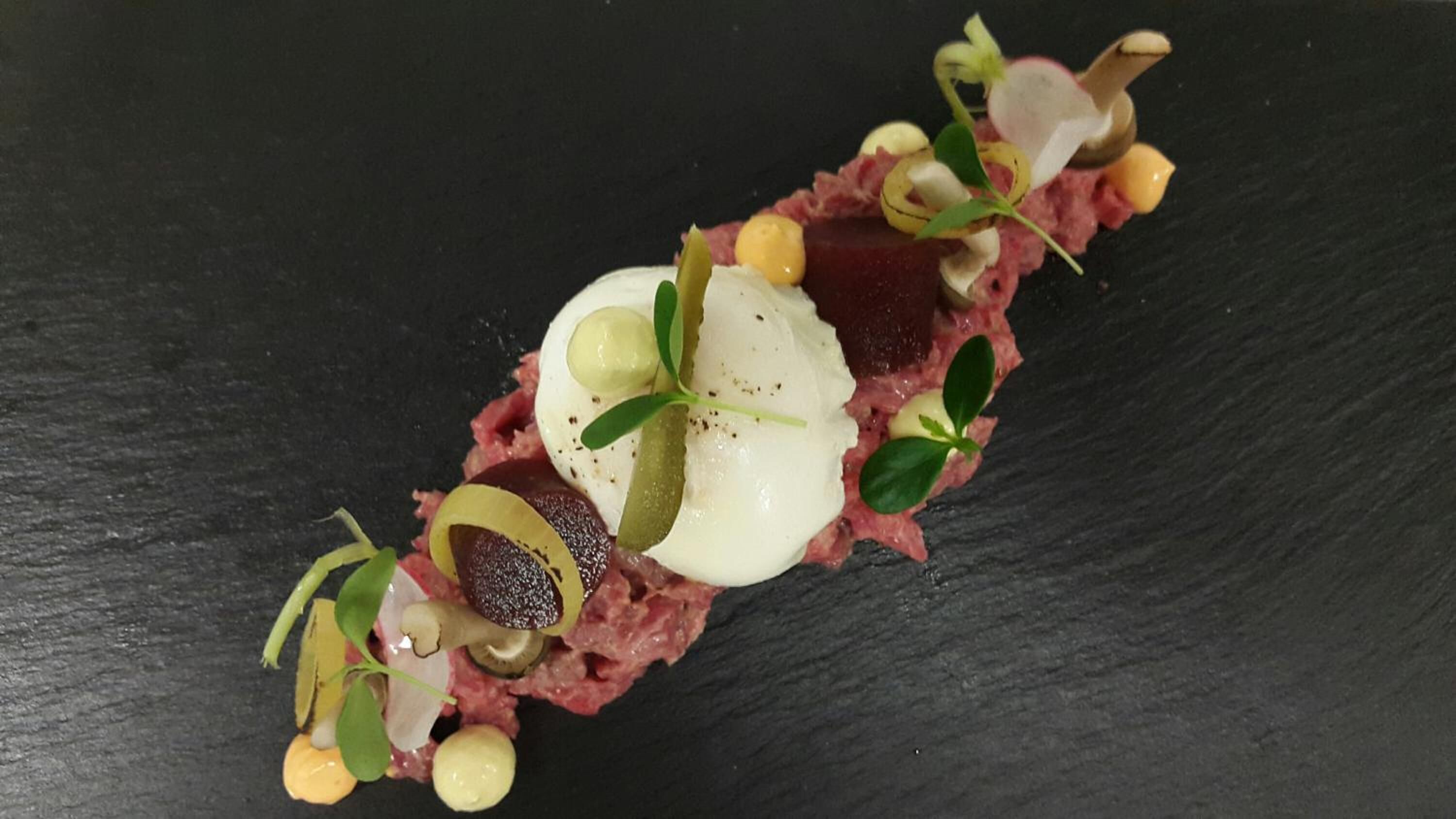 A dish with various garnishes on a black slate plate.