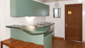 Una cocina con armarios verdes, un banco de madera, una estufa y una puerta de madera.