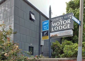 A sign for the Country Glen Motor Lodge with a 'See it here' Sky sign and a 'Novacity' sign.