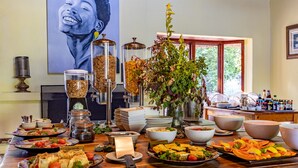 A buffet table with various dishes, including labeled items like 'Cheddar' and 'Salad'. There are also jars of condiments and a vase with flowers.