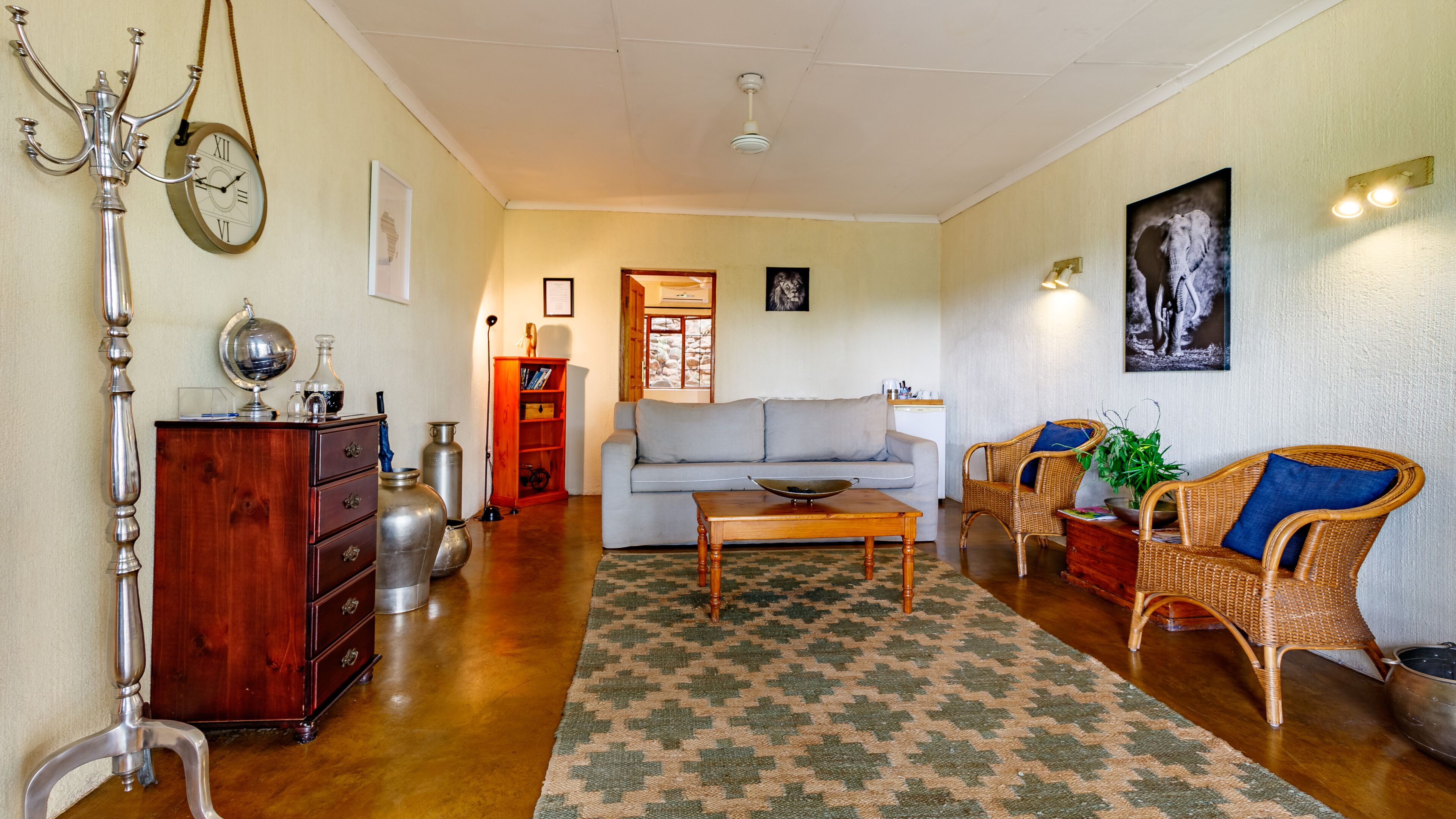 Una sala de estar con un sofá, dos sillones de mimbre, una mesita de centro, un mueble de madera y una lámpara de pie.