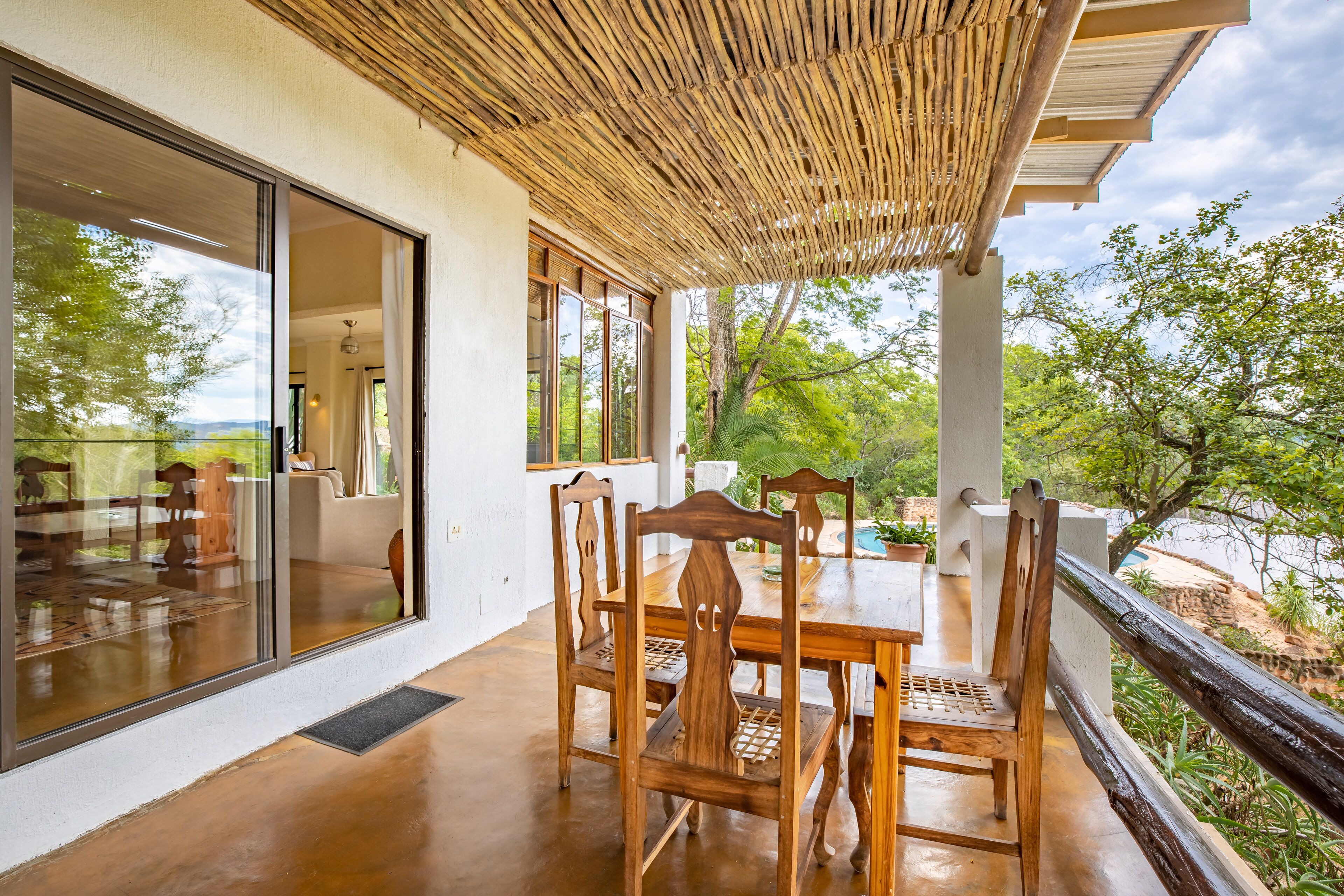 A wooden dining table with chairs, a glass door, and a view of greenery.