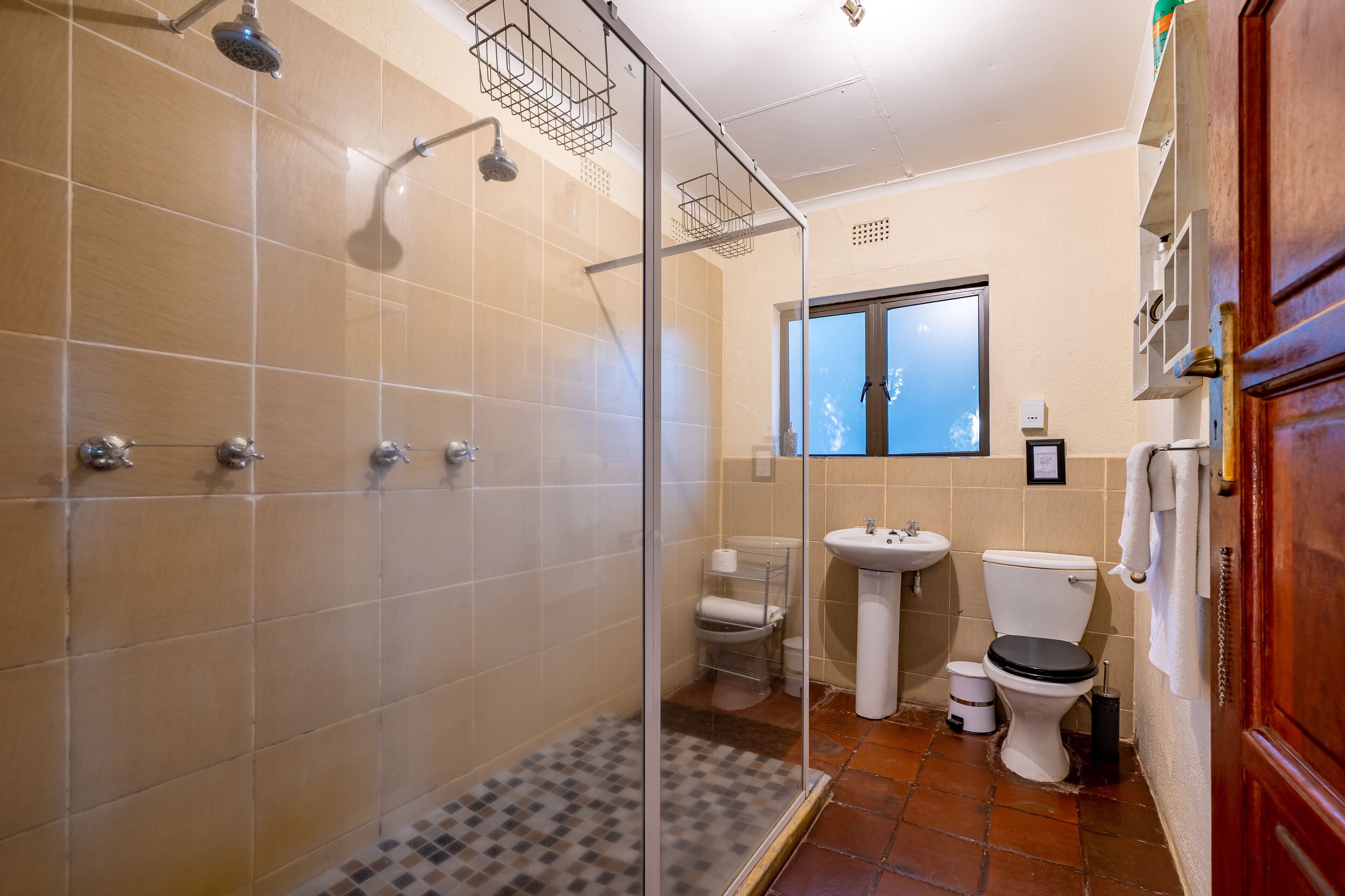 Ein Badezimmer mit Duschkabine, Waschbecken, Toilette und Fenster.