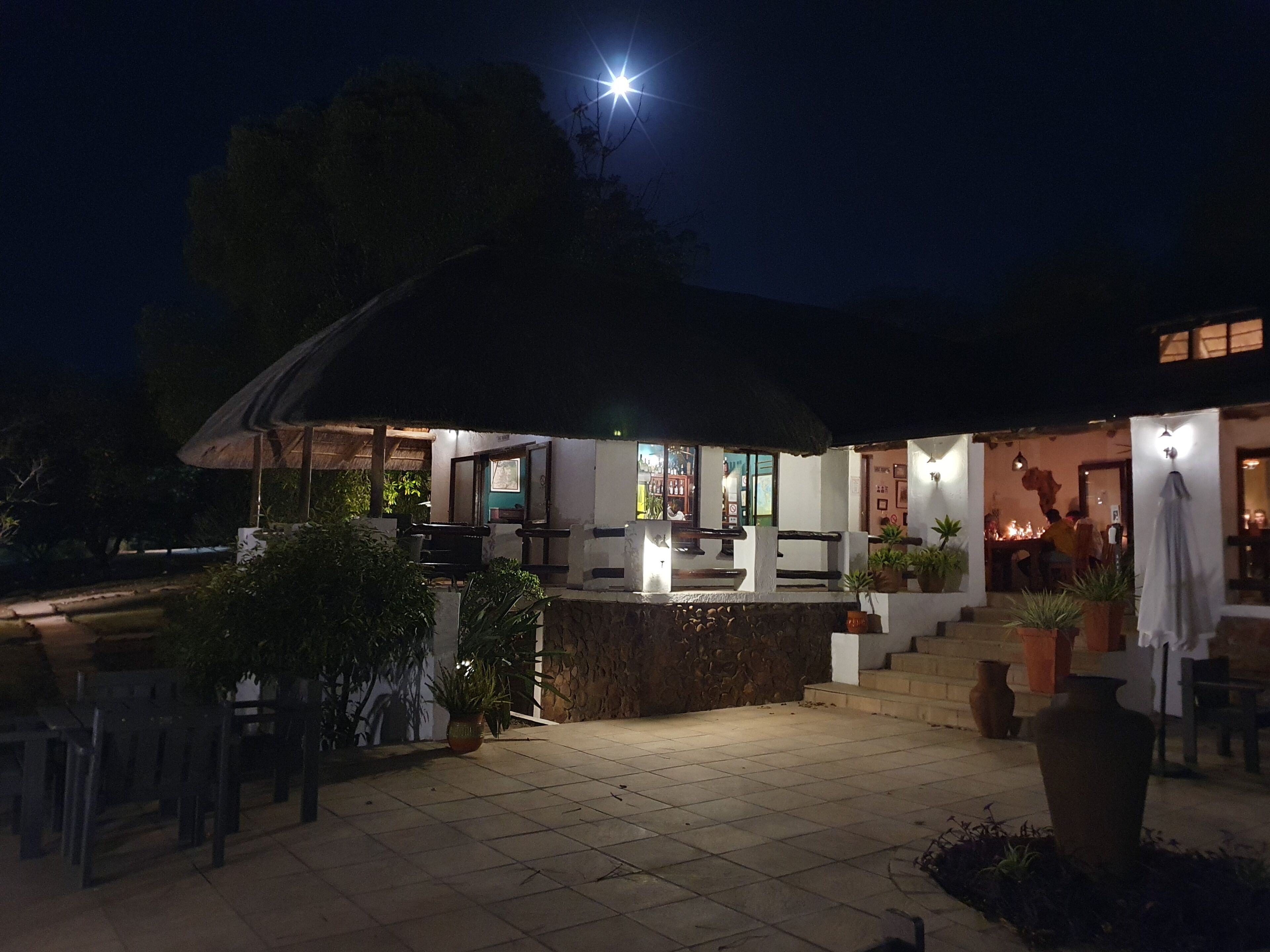 An outdoor patio area with a covered seating area, stone steps, and potted plants.