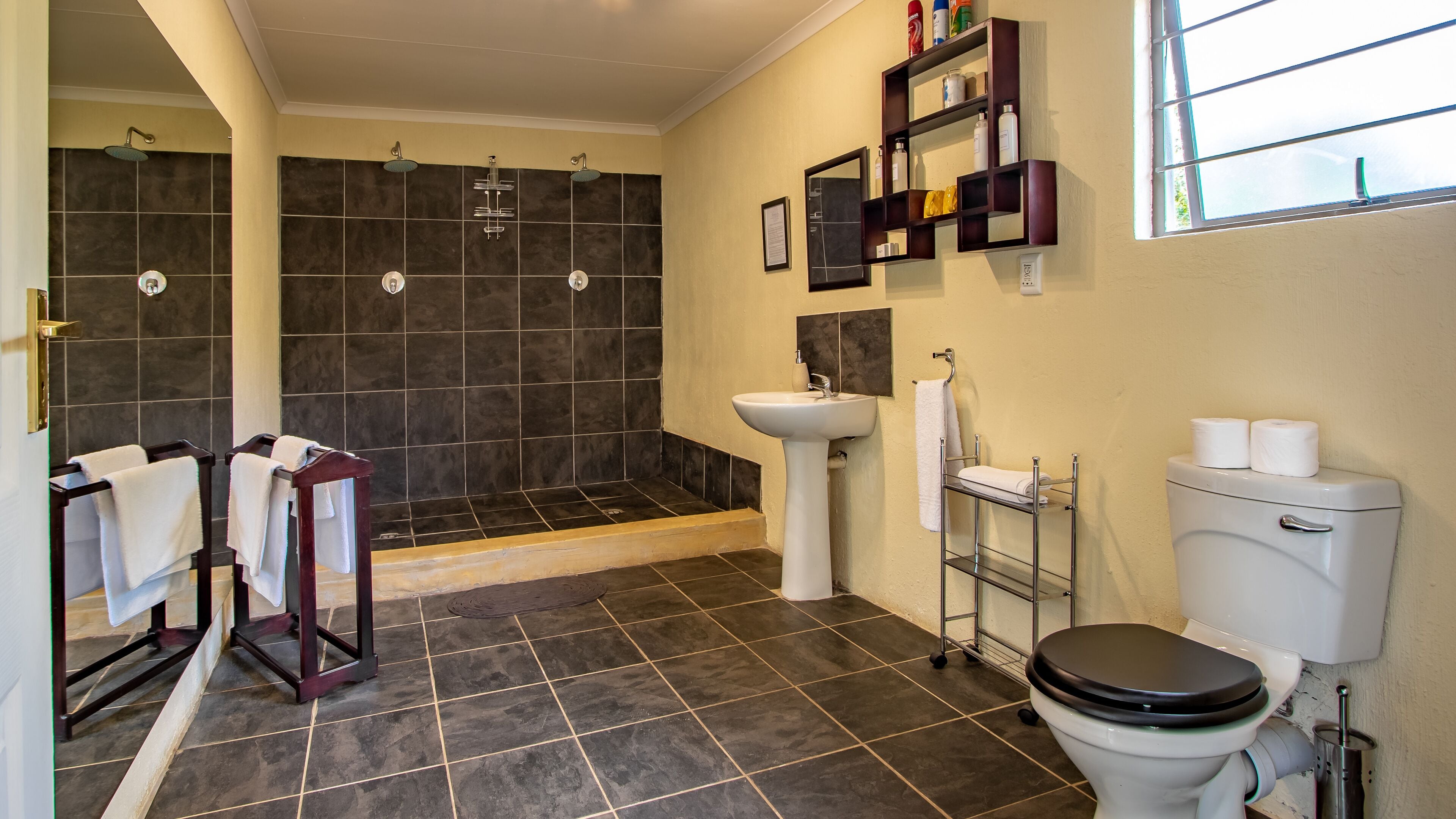 A modern bathroom with a shower, toilet, sink, and towel racks.