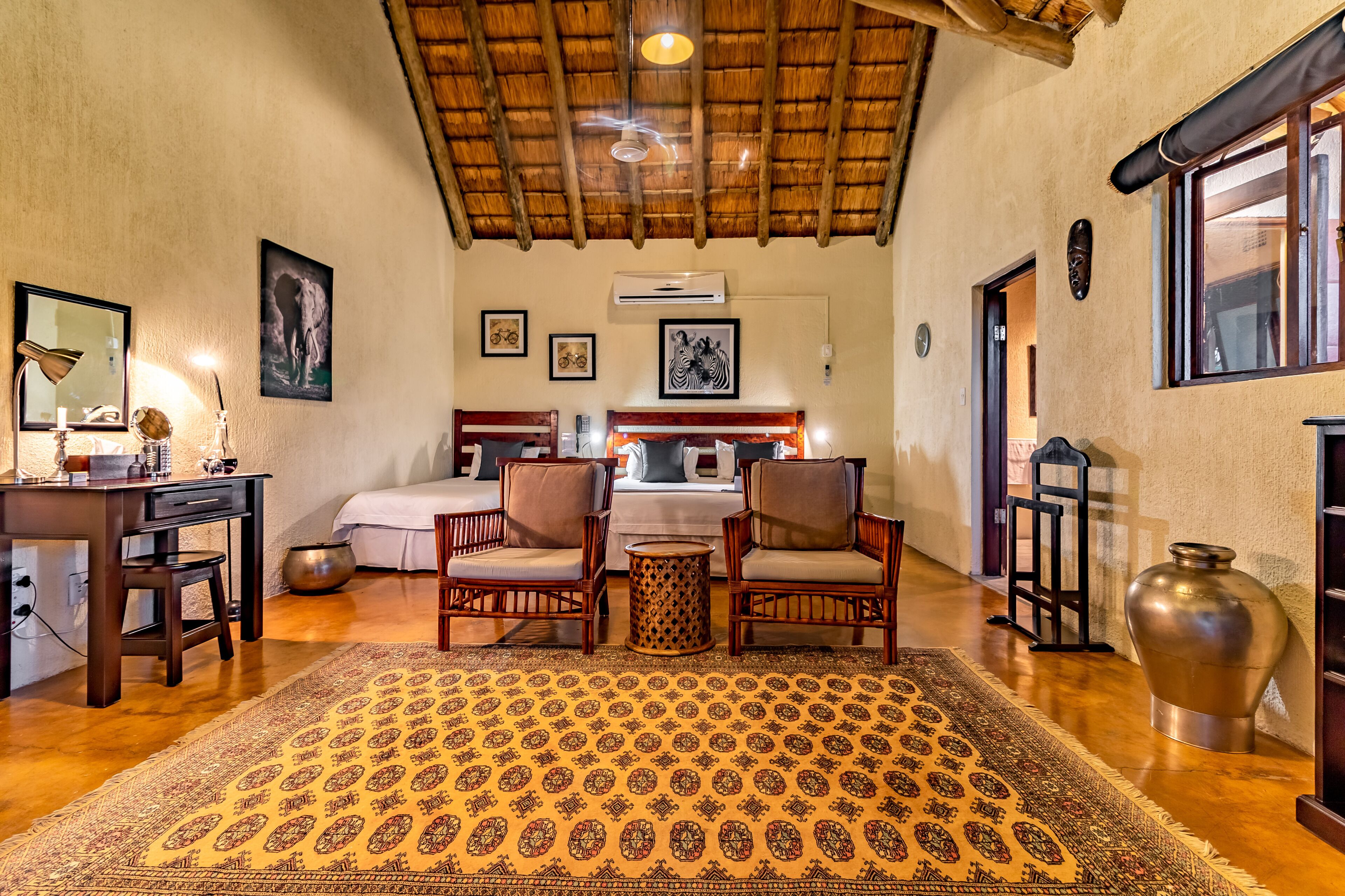 A spacious room with a large bed, two armchairs, a small table, and a patterned rug.