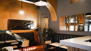 Interior de un restaurante con barra, asientos y una obra de arte grande colgada en la pared.