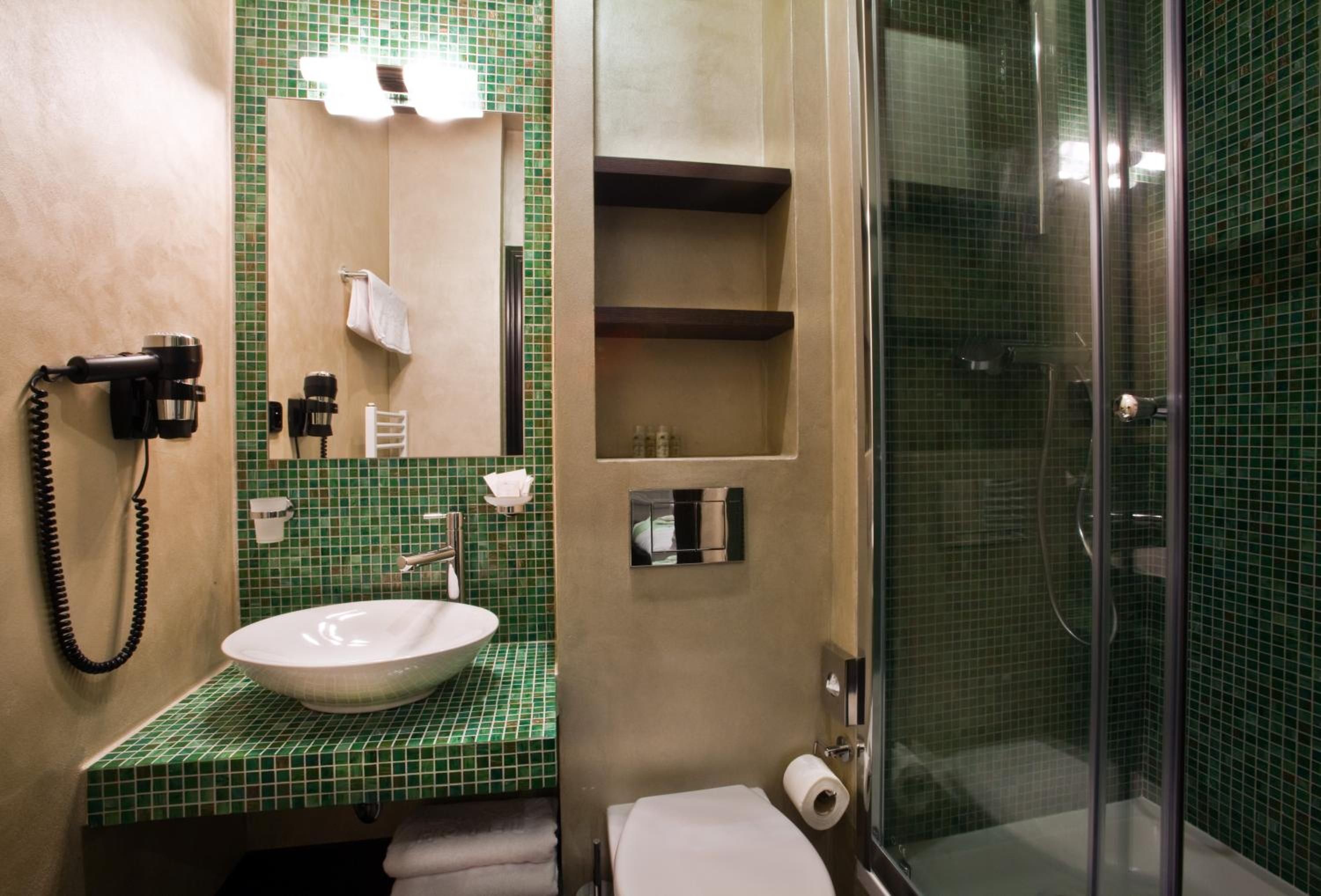 A bathroom with a sink, mirror, towel rack, and a shower area.