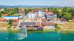A lakeside hotel with multiple buildings, a swimming area, and a fountain.