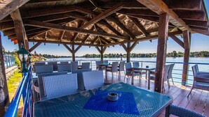 An outdoor patio with a table and chairs, overlooking a body of water. - Hotel Sun (Senec)