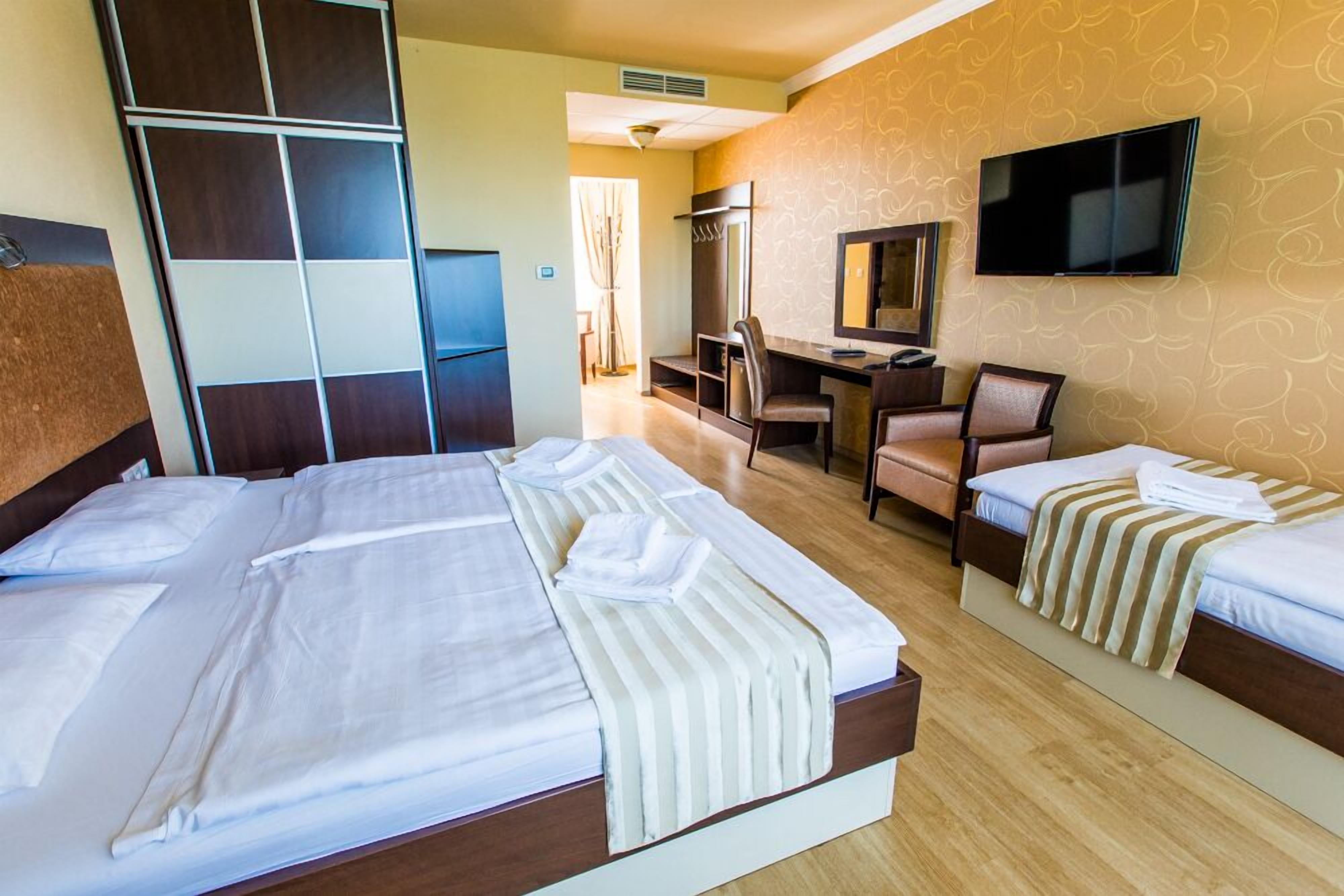 Una habitación de hotel con dos camas, un escritorio, una silla, un televisor y un armario.