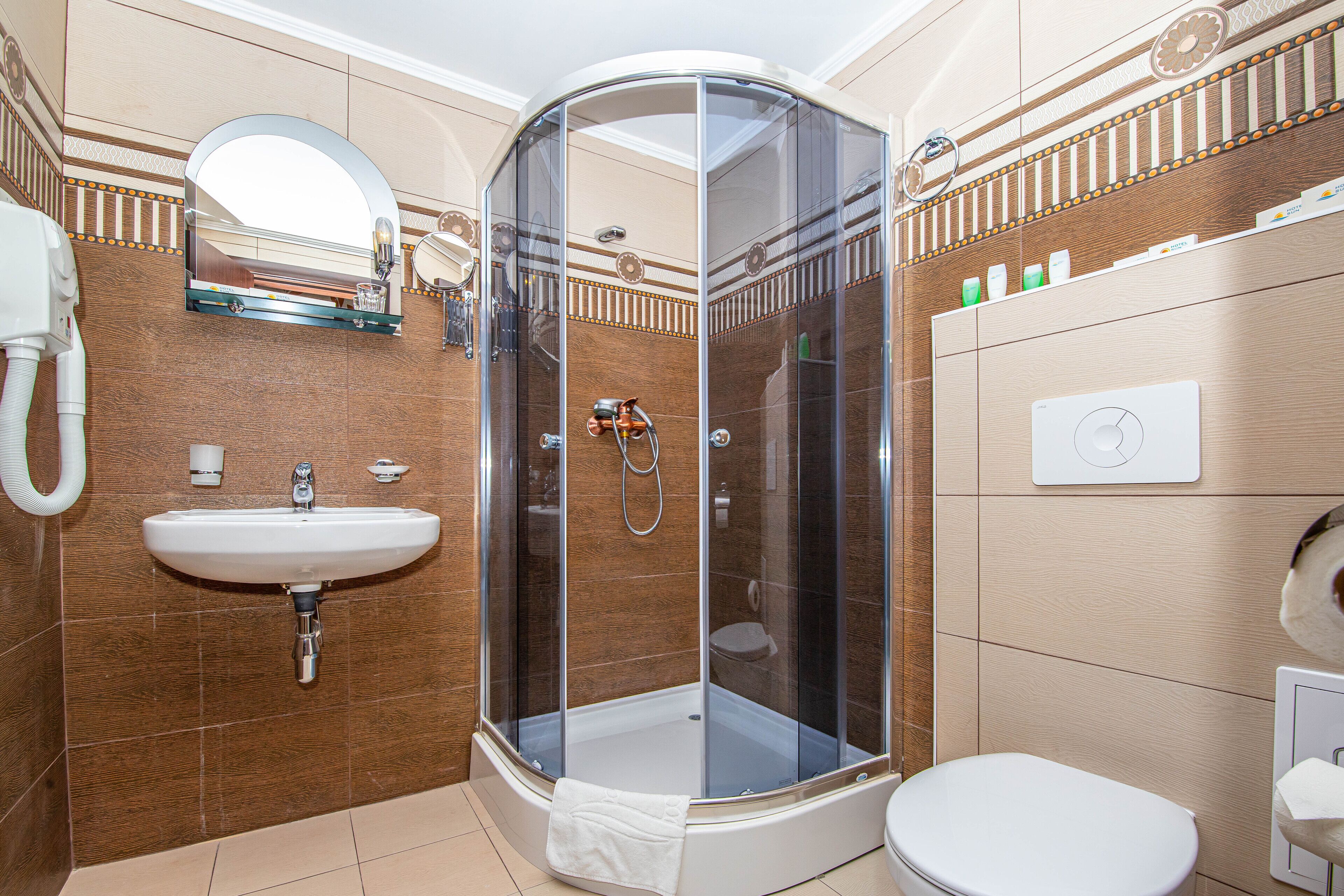 A bathroom with a glass-enclosed shower, a sink, a toilet, and a mirror.