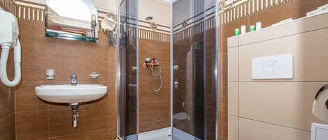 Une salle de bain avec une douche à parois de verre, un lavabo, des toilettes et un miroir.