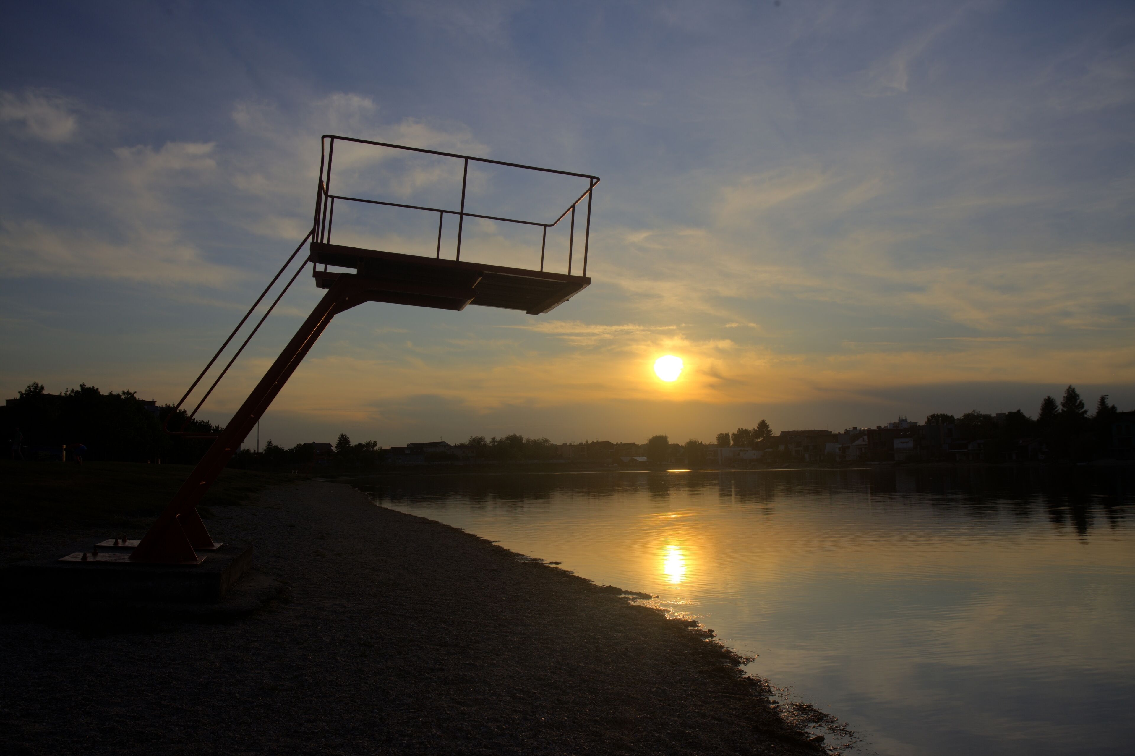 Um cesto de basquete próximo a um lago tranquilo ao pôr do sol.