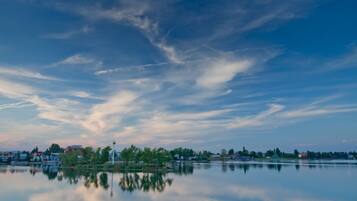 A calm lake with a clear reflection of the sky and buildings.