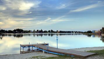 Un lago tranquilo con un muelle de madera y una señal de estacionamiento.