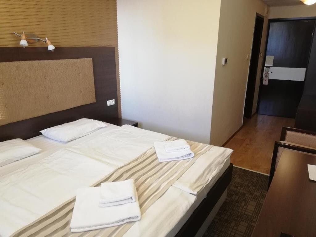 Una habitación de hotel con cama, cabecera, escritorio y puerta.