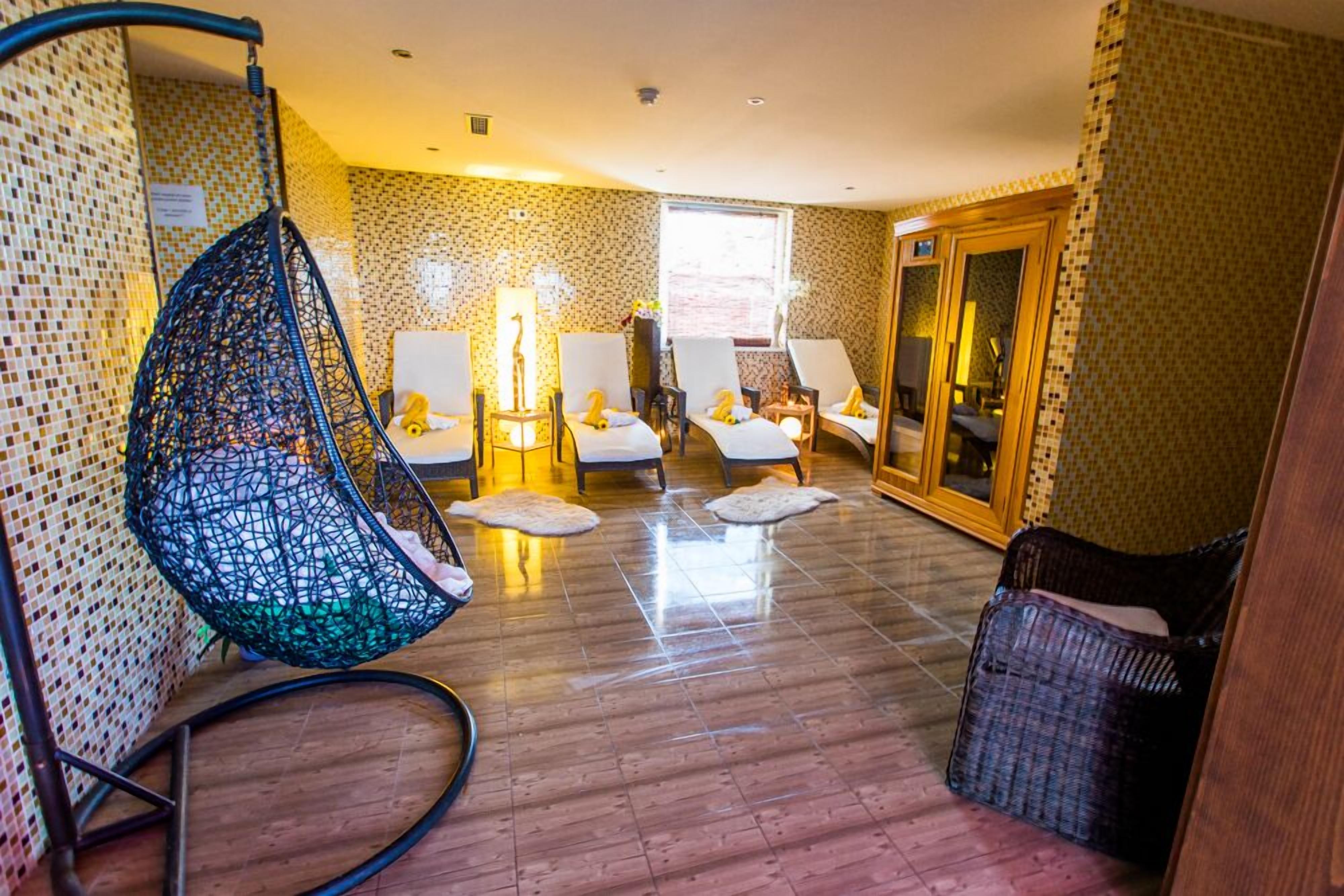 A room with a hanging chair, two massage tables, and a wicker chair.