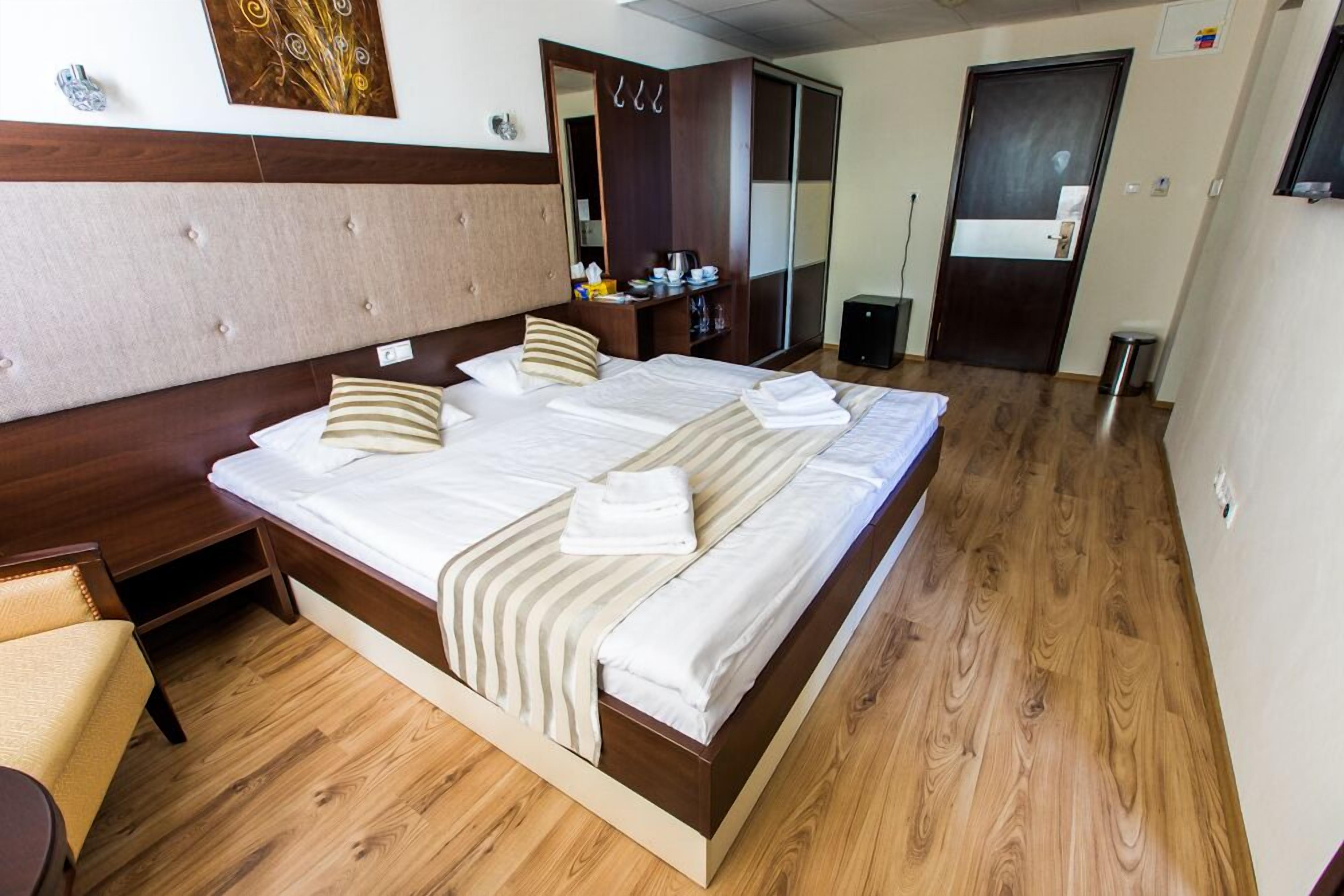 Habitación de hotel con una cama grande, suelo de madera, un armario y una pequeña zona de estar.