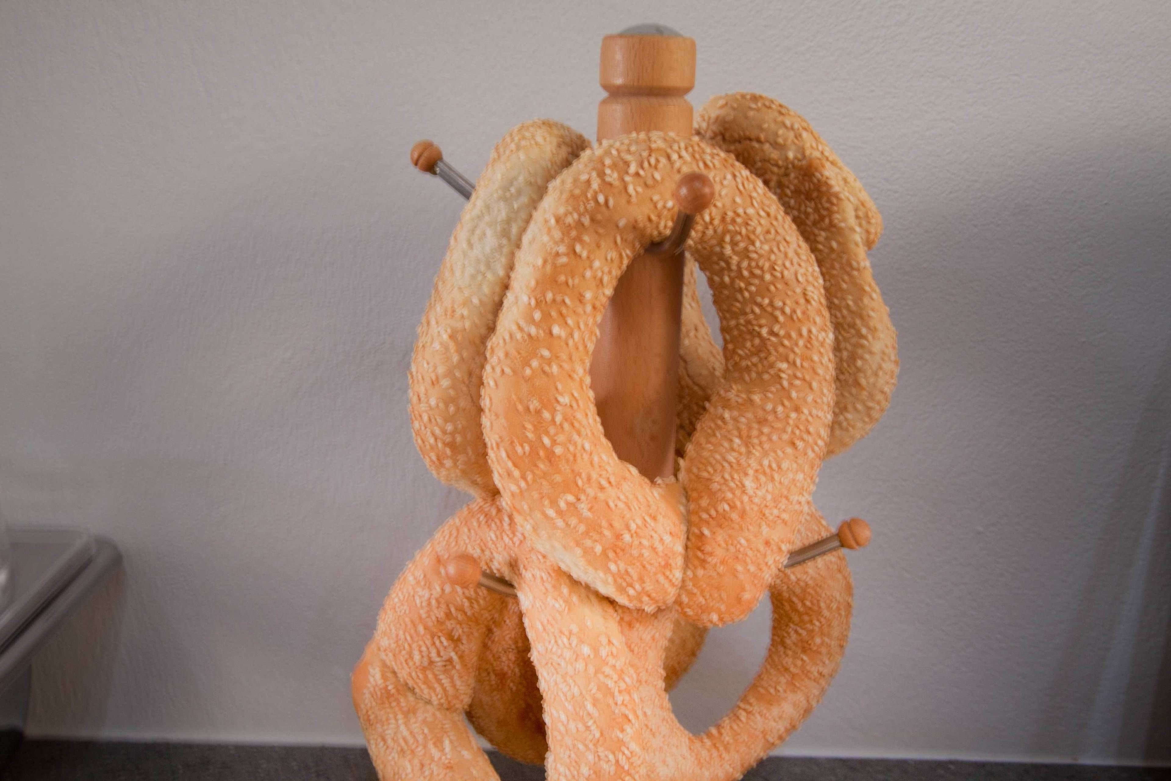 Een houten standaard met een brood in de vorm van een lus, bedekt met sesamzaad.