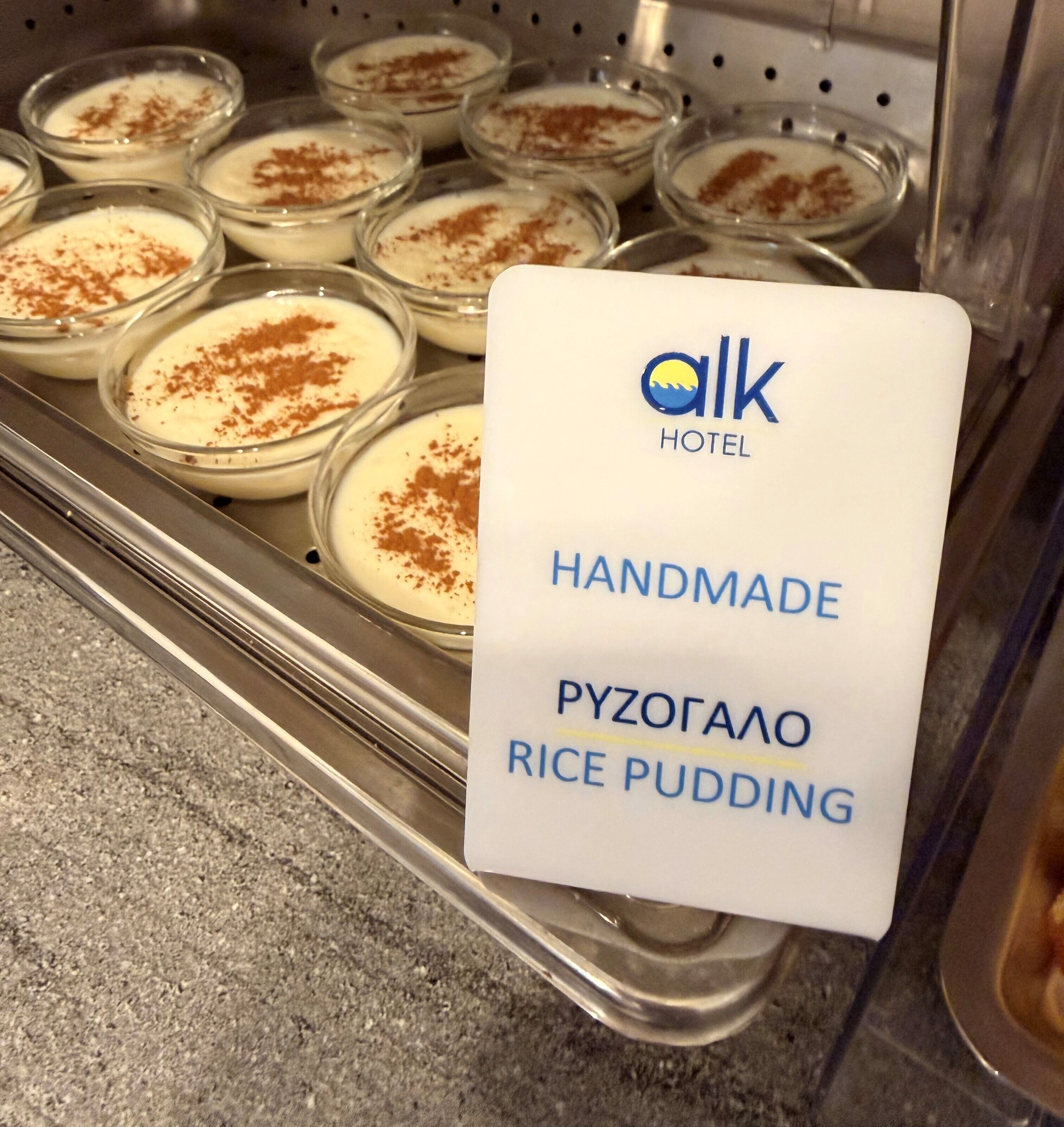 Ein Tablett mit selbstgemachtem Reispudding in Gläsern, mit einem Schild, das angibt, dass er vom Alk Hotel stammt.