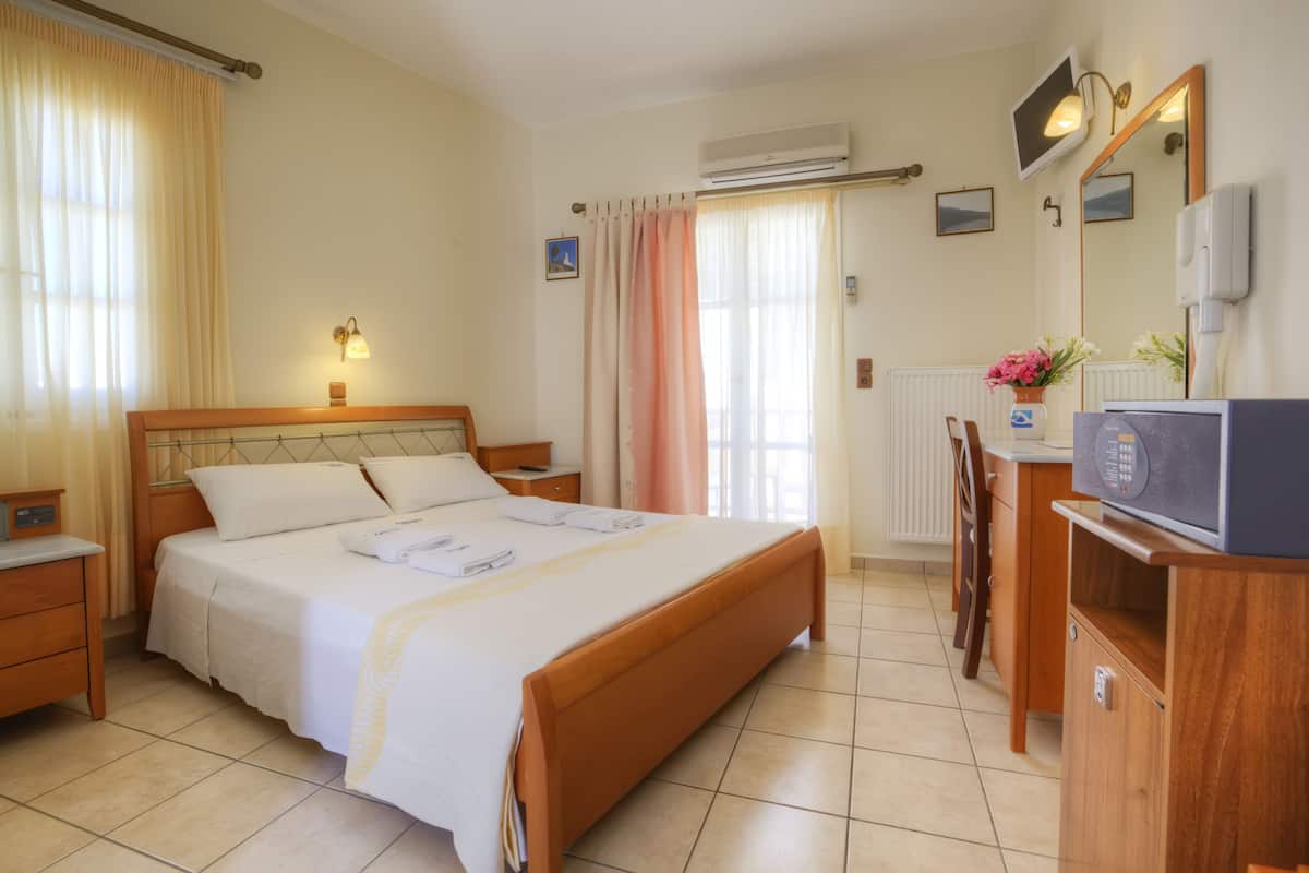 Ein Hotelzimmer mit einem Bett, Nachttischen, einem Fernseher, einem Schreibtisch und einem Sessel.