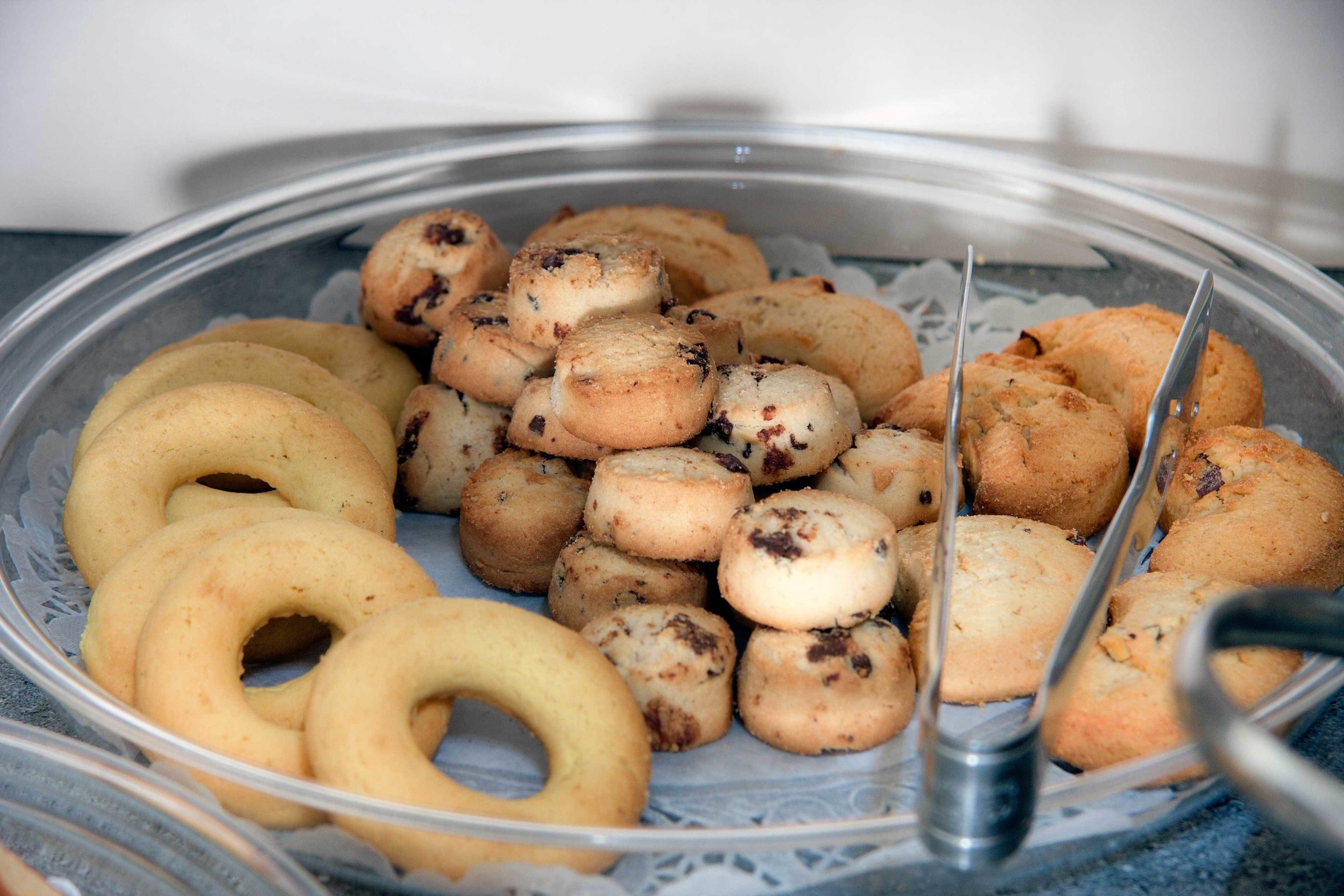 A tray of assorted pastries, including ring-shaped and round cookies, arranged on a clear glass plate.