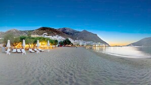 Una playa con edificios blancos, una montaña y un mar tranquilo.