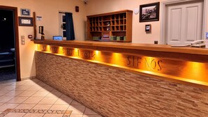 Un mostrador de recepción de hotel con una superficie de madera, una zona de espera y una puerta al fondo.