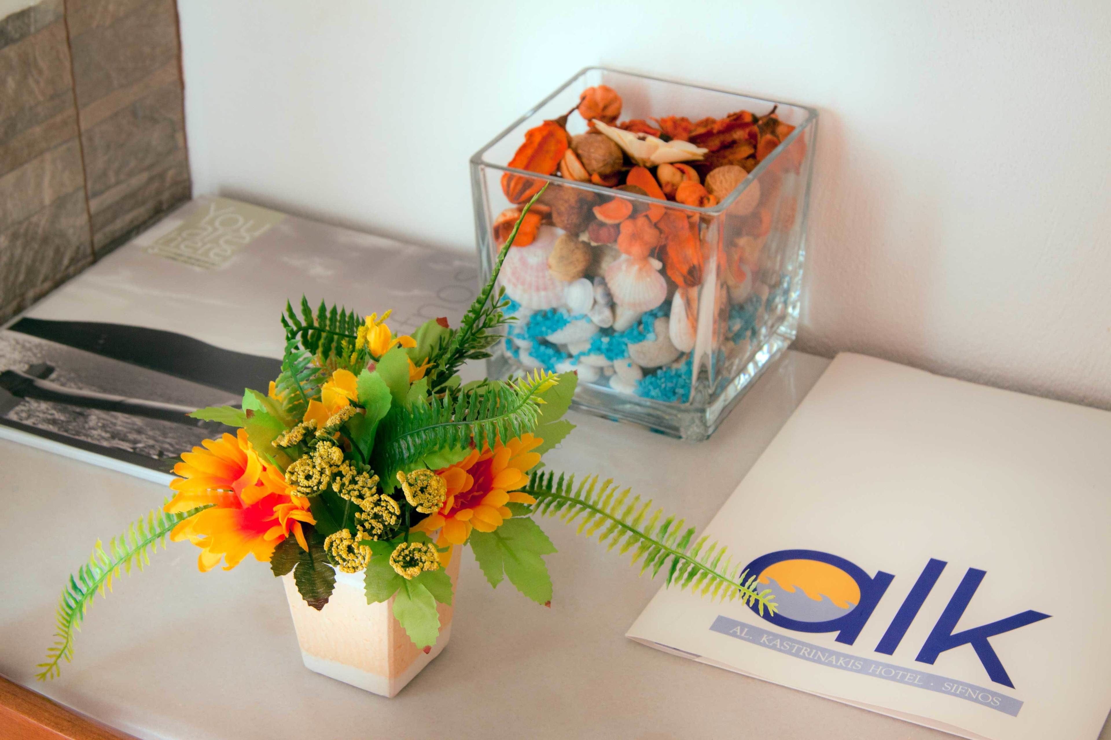 A glass vase with a floral arrangement and a glass container with seashells on a table.