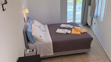 Un dormitorio ordenado con cama, mesita de noche y vistas al exterior.