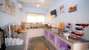 Una barra de desayuno con máquinas de café, diversas opciones de comida y un televisor en la pared.