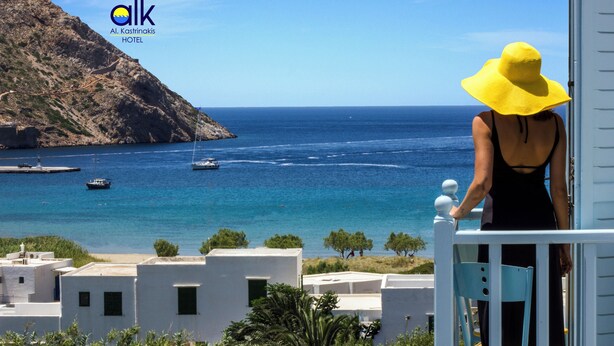 Un balcón con vista al mar, barcos y un paisaje montañoso.