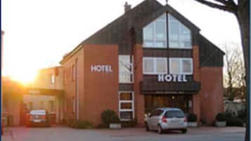 Ein Hotel mit auffälligem Schild, einer Ziegel-Fassade und einem parkenden Auto davor.