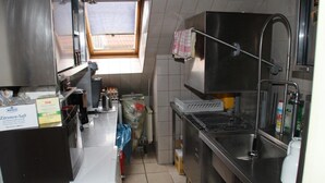 A compact kitchen with a window, stainless steel appliances, and a tiled backsplash. - Einfelder Hof (Neumuenster)