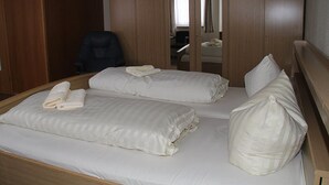 A hotel room with two beds, wooden wardrobe, and a chair. - Einfelder Hof (Neumuenster)