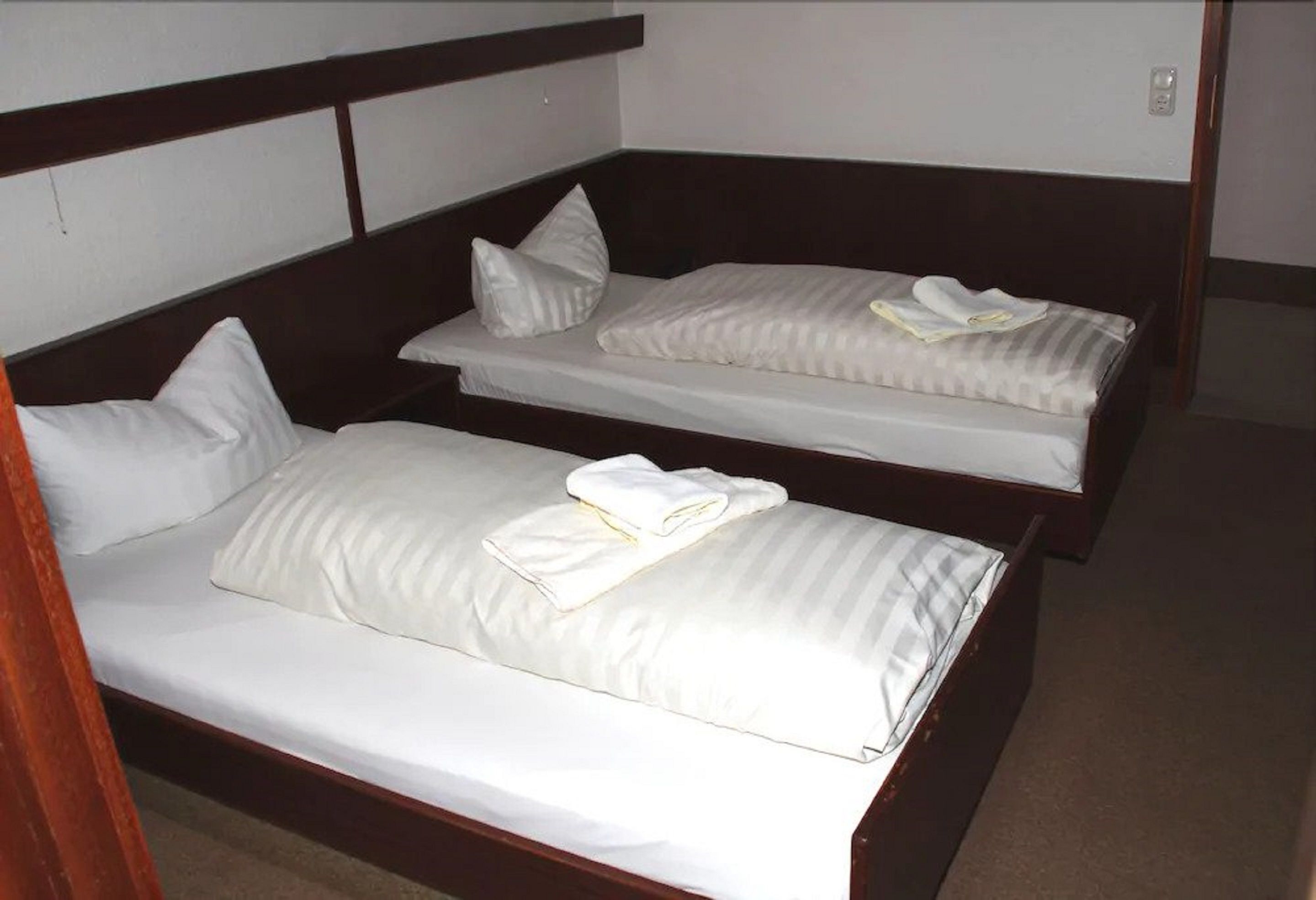 Una habitación con dos camas individuales, cada una con ropa de cama y almohadas blancas.