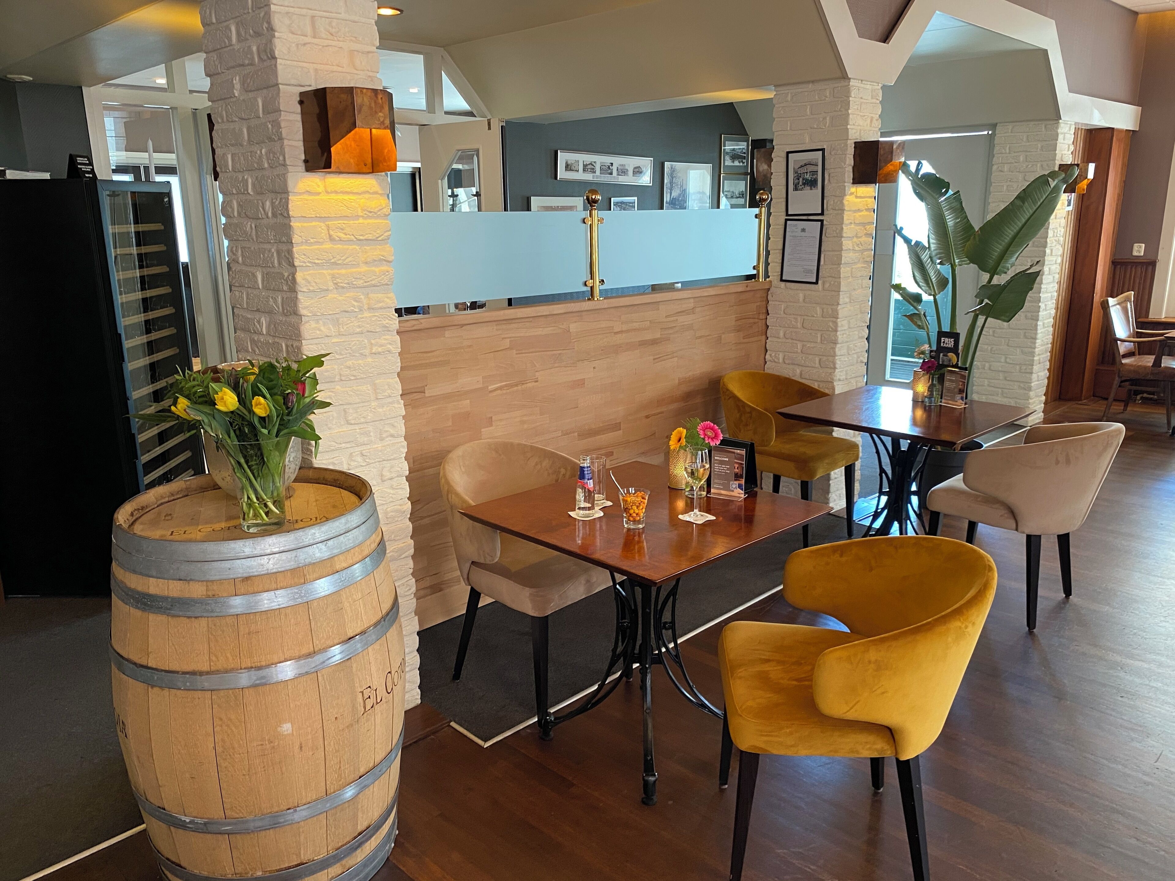 L’intérieur d’un restaurant avec des tables en bois, des chaises jaunes et un grand tonneau.