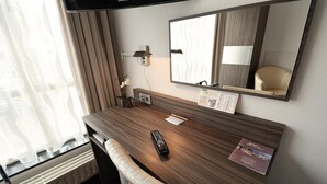 A hotel room with a wooden desk, a remote control, a lamp, and a mirror. - Hotel Faber (Hoogezand)