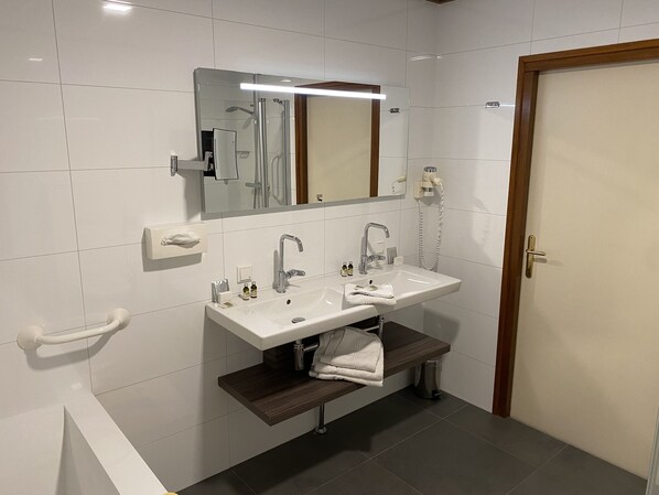 A modern bathroom with a white sink, two faucets, a mirror, and a towel rack. - Hotel Faber (Hoogezand)