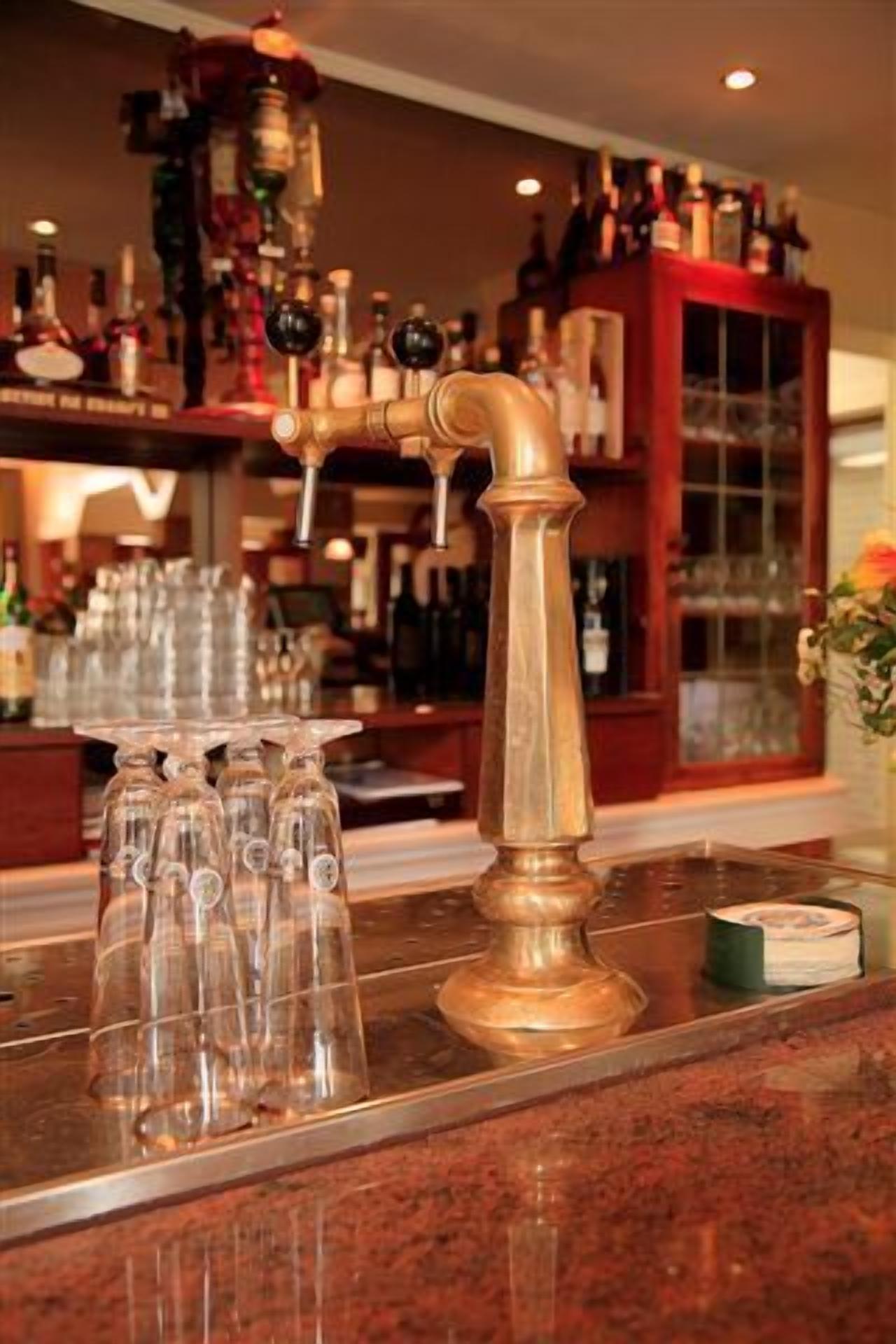 A bar area with a copper tap and multiple glasses on the counter.