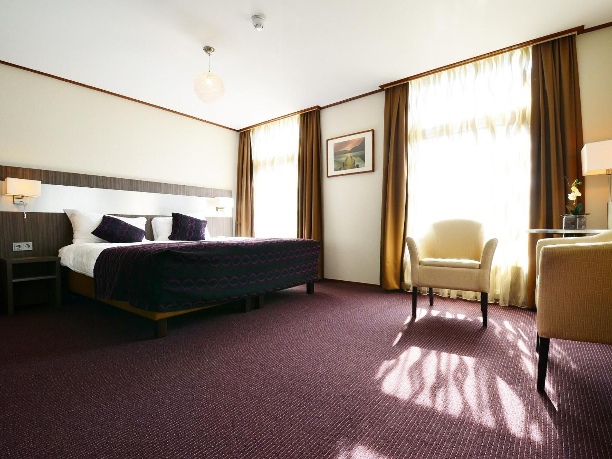 Habitación de hotel con una cama grande, un escritorio, una silla y una ventana con cortinas.