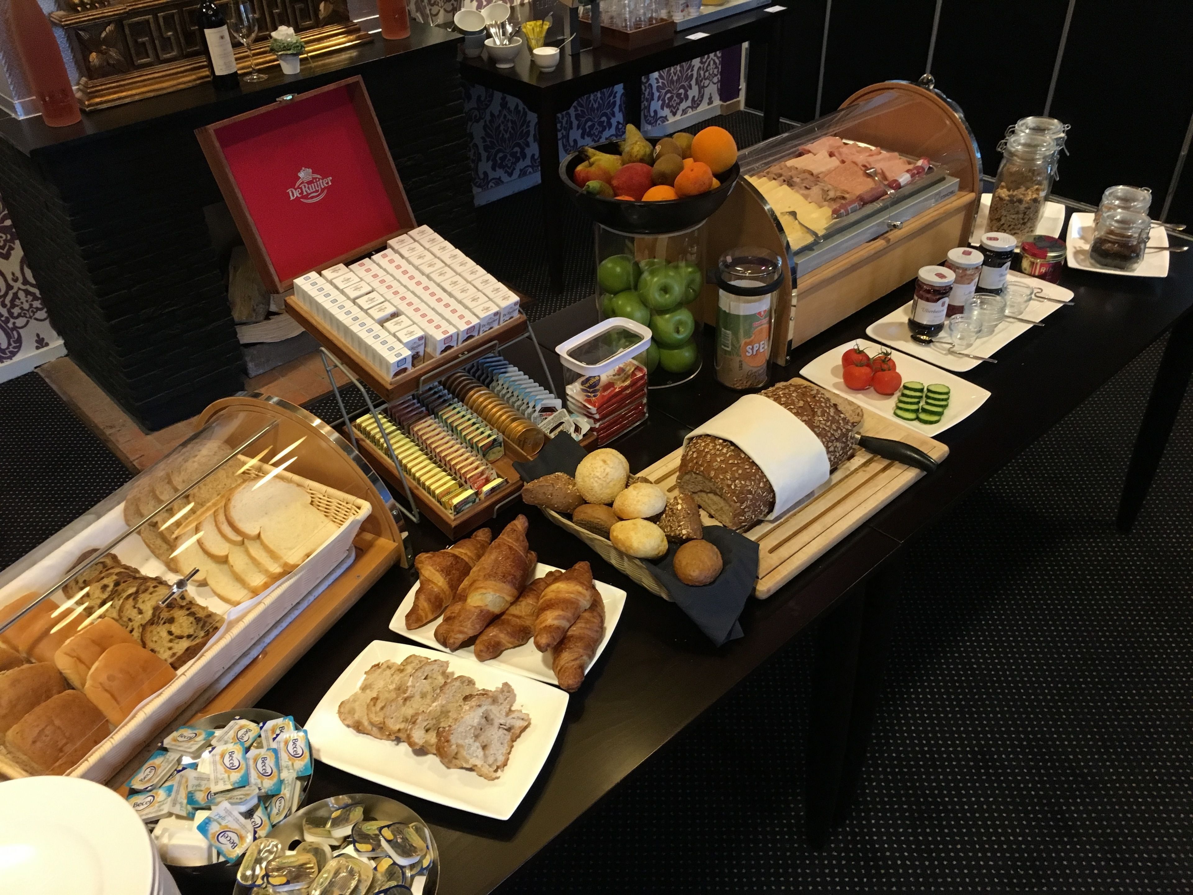 En buffet med forskellige spisemuligheder, blandt andet brød, kager, frugt og tilbehør.