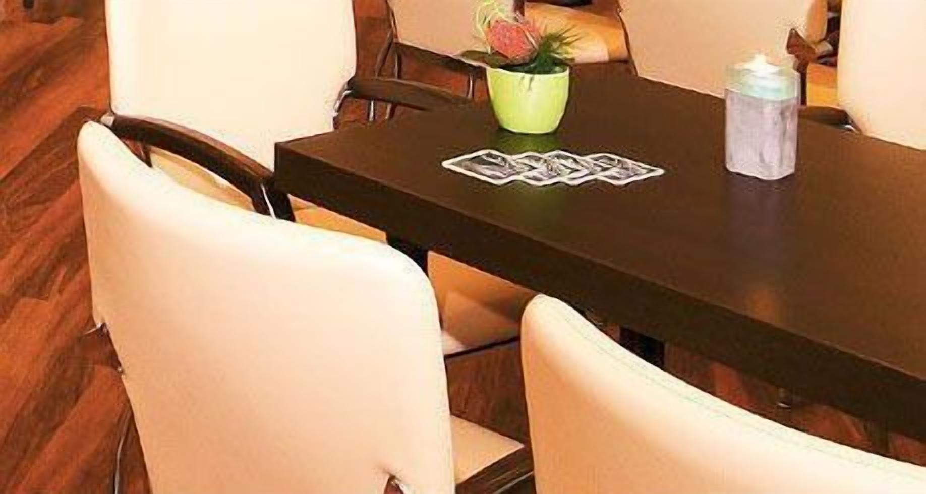 A dining table with chairs, a green vase with flowers, and a water bottle.