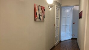 A hallway with wooden flooring, white walls, and a door at the end. - Elios Rooms (Catania)