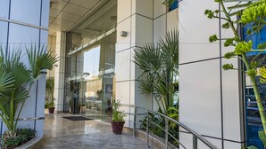 A modern building with a glass entrance, potted plants, and a metal railing. - Imperial Suites Hotel (Doha)